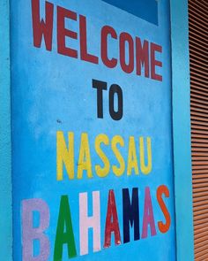 a welcome sign is painted on the side of a building with words in different colors