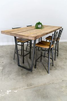 a wooden table with four chairs and a plant on top of it in an empty room