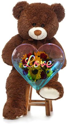 a brown teddy bear holding a heart shaped vase filled with sunflowers