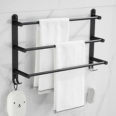 two towel racks are hanging on the wall next to towels and a teddy bear ornament