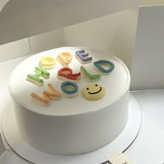 a white cake with colorful letters and smiley faces on it's frosting surface