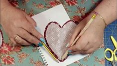 a woman is making a heart out of paper