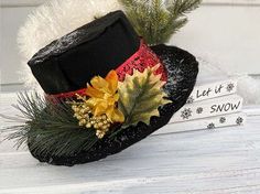 a black hat with yellow and red flowers on it sitting next to two books that read let it snow