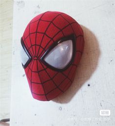 a close up of a spiderman mask on a white surface with the eyes open