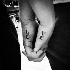 two people holding hands with the words love tattooed on their wrists in black and white