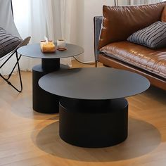 two black tables sitting next to each other in front of a brown couch and chair