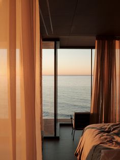 a bedroom with an ocean view is shown from the bed and curtains on the windows