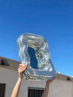 a person holding up a large mirror in the air