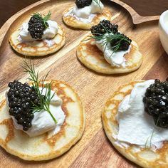 small pancakes with blackberries and whipped cream on a wooden tray next to a bowl