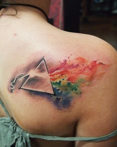 the back of a woman's shoulder with a triangle tattoo on it