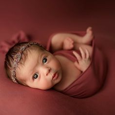 a baby laying on its back wearing a headband and looking up at the camera