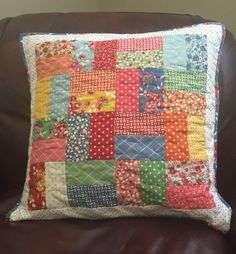 a colorful patchwork pillow sitting on top of a brown couch