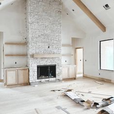 an empty living room with white brick fireplace and unfinished wood flooring in the foreground