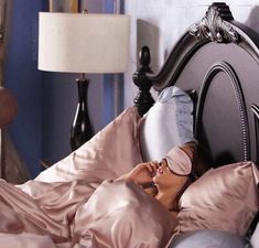 a woman is laying in bed with her eyes closed and nose covered by a blindfold