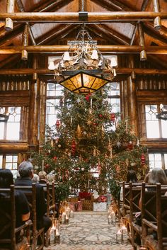 a large christmas tree is in the middle of a room with pews and candles