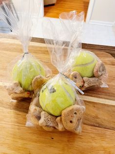 two tennis balls wrapped in plastic on top of a wooden cutting board with bags of them