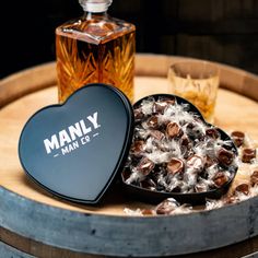 a heart shaped box filled with chocolates next to a bottle of whiskey