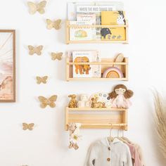 the wall is decorated with wooden shelves and butterfly magnets on them, along with bookshelves