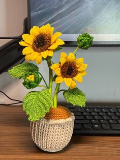 a crocheted vase with two sunflowers in front of a computer keyboard