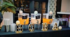 a table topped with candles and containers filled with orange liquid next to other items that spell out the word b o b