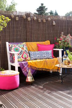 an outdoor seating area is decorated with colorful pillows