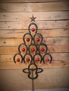 a christmas tree made out of horseshoes and apples on a wooden wall with stars