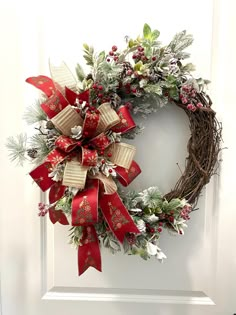 a christmas wreath with red and gold bows hanging on the front door, decorated with greenery