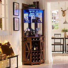 a wooden cabinet with wine glasses and bottles on it in a living room next to a dining room table