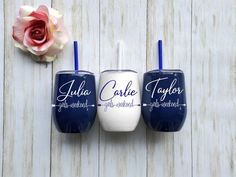 three blue and white tumblers sitting on top of a wooden table next to a pink flower