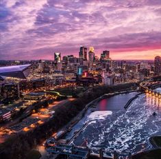 an aerial view of a city at dusk with the sun setting in the distance and water running through it