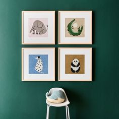 four framed pictures hang on the wall above a chair in a room with green walls