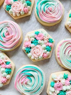 many decorated cookies are on a sheet of wax paper with icing and flower decorations