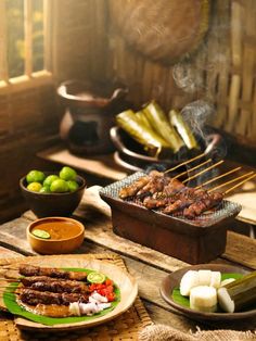 there are many different foods on the table and one is being grilled with skewers