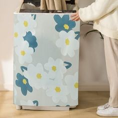 a person standing next to a flowered box with utensils in it's drawer