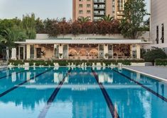 an empty swimming pool in front of a tall building with trees on the top floor