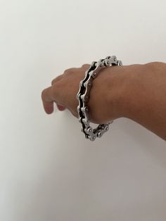 a person's hand holding onto a chain bracelet on a white background with space for text