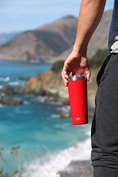 a person holding a red cup near the ocean