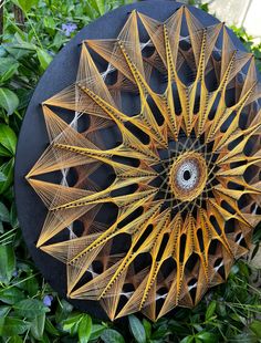 an intricately designed umbrella sitting in the middle of some bushes and plants, with leaves surrounding it