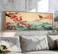 a painting hanging on the wall above a couch in front of a potted plant