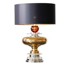 a table lamp with a black shade on top and a gold base, sitting against a white background