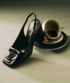 a pair of black high heeled shoes next to a cup of coffee