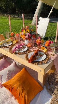 a table set up with plates and candles for an outdoor dinner or picnic party in the grass