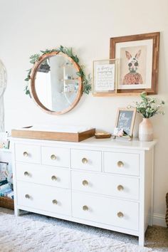 there is a dresser with many drawers and pictures on the wall