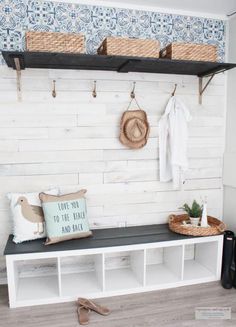 a bench with some baskets on top of it and two coats hanging from the hooks