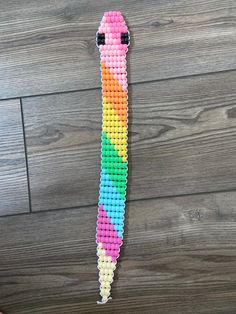 a colorful beaded snake hanging on a wooden wall