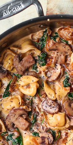 pasta with mushrooms and spinach in a skillet on a wooden table, ready to be eaten