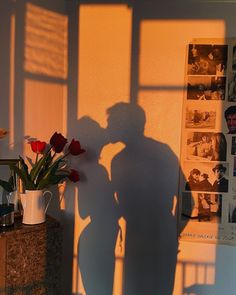 the shadow of a man standing next to a vase with flowers