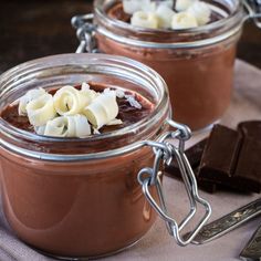 two glass jars filled with chocolate pudding on top of a table