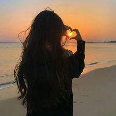 a woman standing on top of a beach next to the ocean