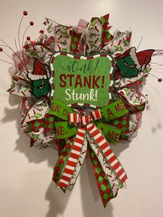 a green and red christmas wreath with the words stink stank stuck on it's side